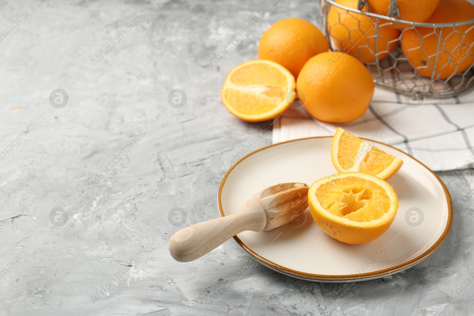 Wooden juicer and fresh oranges on grey table. Space for text Photo of Wooden juicer and fresh oranges on grey table. Space for text