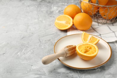Photo of Wooden juicer and fresh oranges on grey table. Space for text