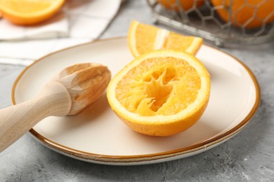 Photo of Wooden juicer and fresh oranges on grey table, closeup