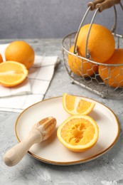 Photo of Wooden juicer and fresh oranges on grey table, closeup