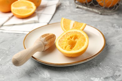 Photo of Wooden juicer and fresh oranges on grey table, closeup