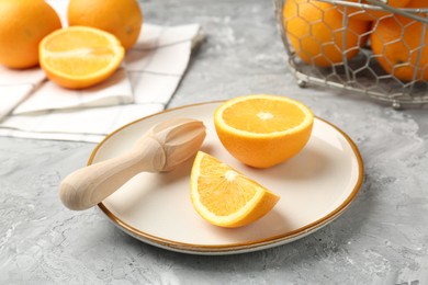 Photo of Wooden juicer and fresh oranges on grey table, closeup