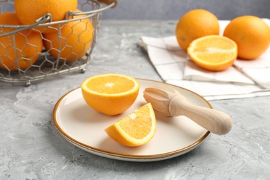 Photo of Wooden juicer and fresh oranges on grey table, closeup