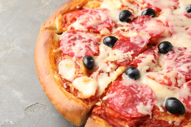 Photo of Tasty pizza with salami, cheese and olives on grey table, closeup