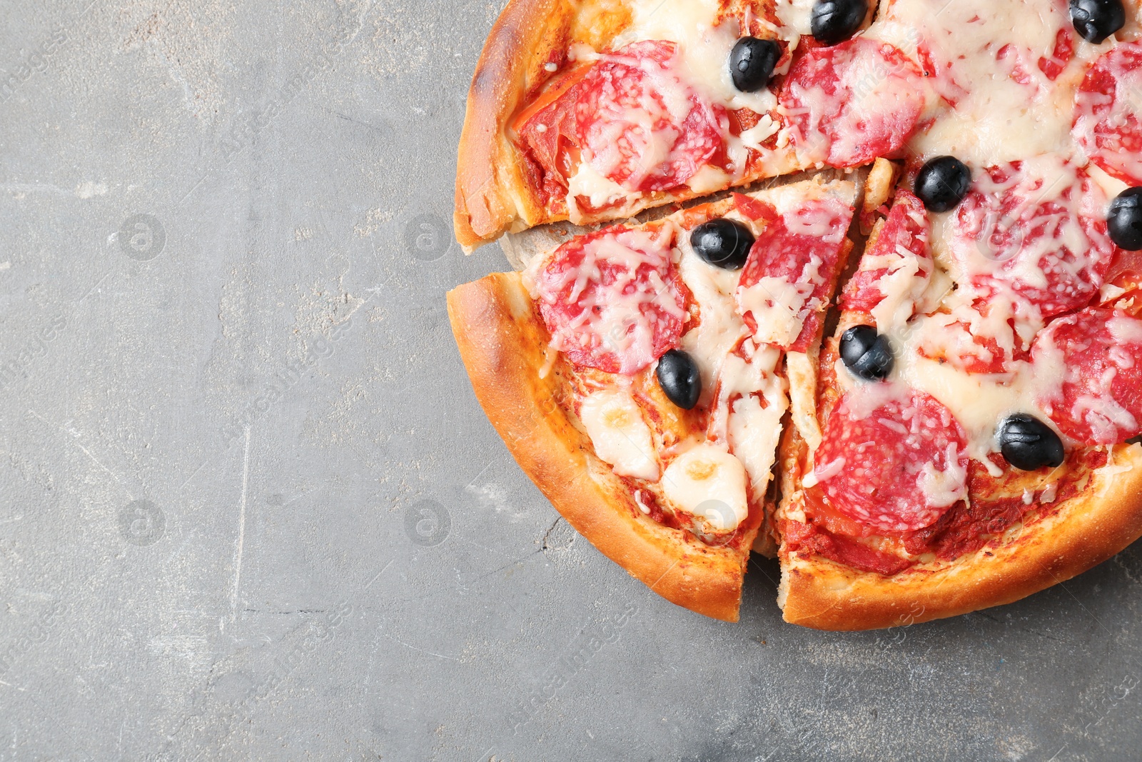 Tasty pizza with salami, cheese and olives on grey table, top view. Space for text Photo of Tasty pizza with salami, cheese and olives on grey table, top view. Space for text