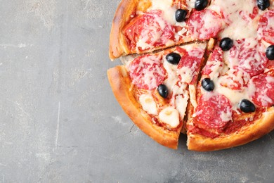 Photo of Tasty pizza with salami, cheese and olives on grey table, top view. Space for text