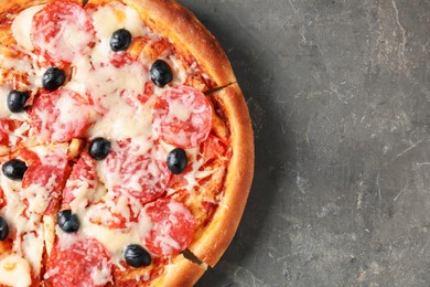 Photo of Tasty pizza with salami, cheese and olives on grey table, top view. Space for text