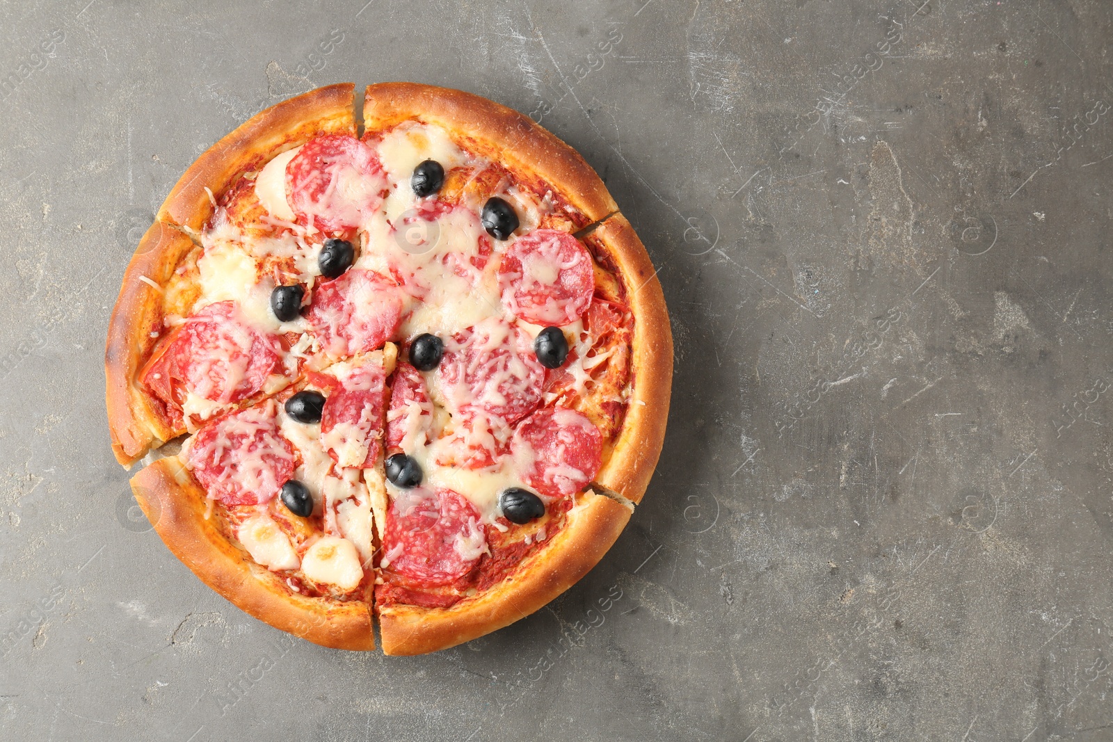 Tasty pizza with salami, cheese and olives on grey table, top view. Space for text Photo of Tasty pizza with salami, cheese and olives on grey table, top view. Space for text