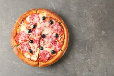 Photo of Tasty pizza with salami, cheese and olives on grey table, top view. Space for text
