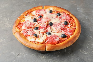 Photo of Tasty pizza with salami, cheese and olives on grey table, closeup