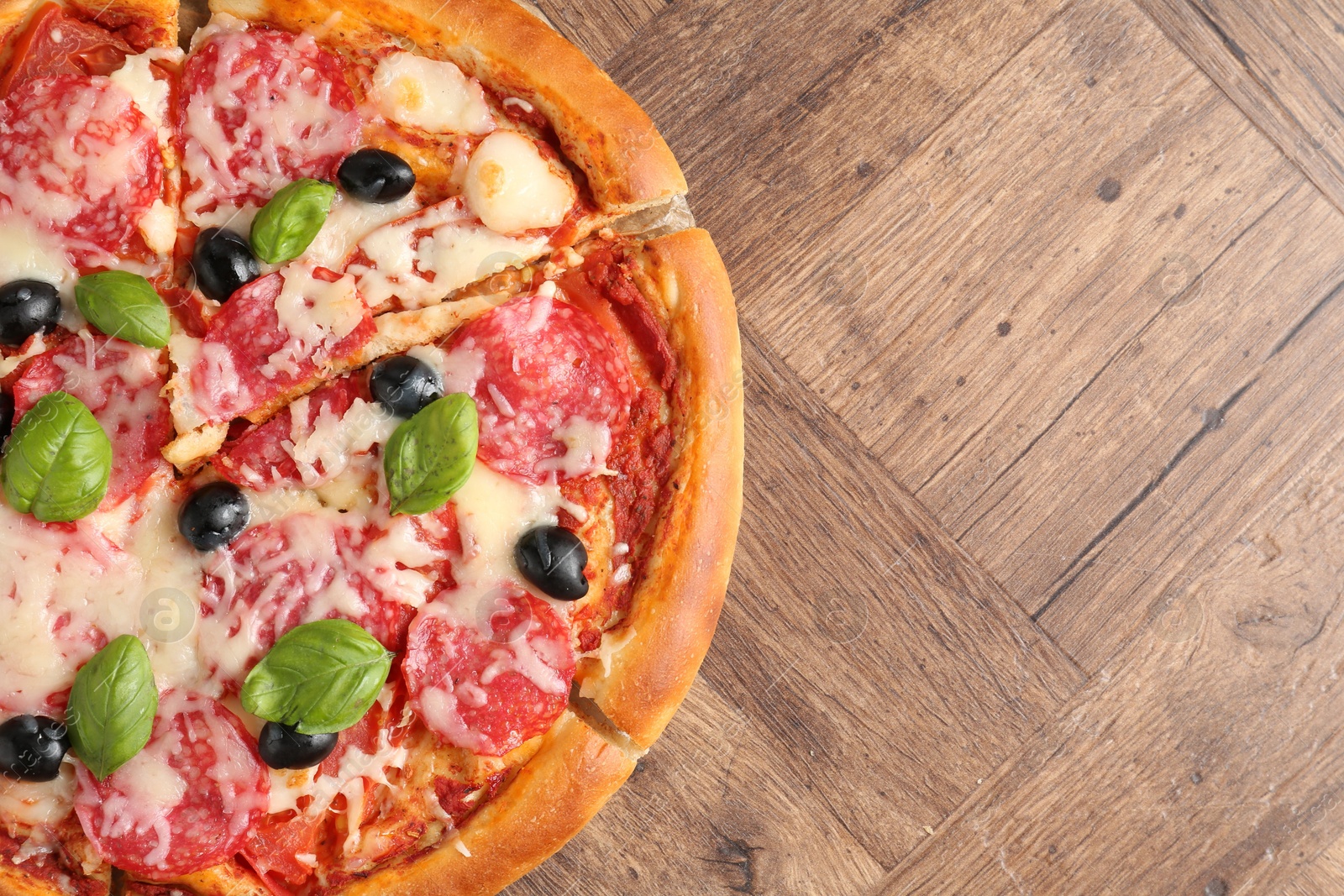 Tasty pizza with salami, cheese, basil and olives on wooden table, top view. Space for text Photo of Tasty pizza with salami, cheese, basil and olives on wooden table, top view. Space for text