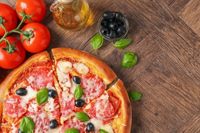 Photo of Tasty pizza and ingredients on wooden table, flat lay. Space for text