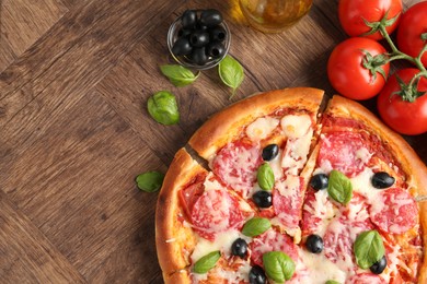 Photo of Tasty pizza and ingredients on wooden table, flat lay. Space for text
