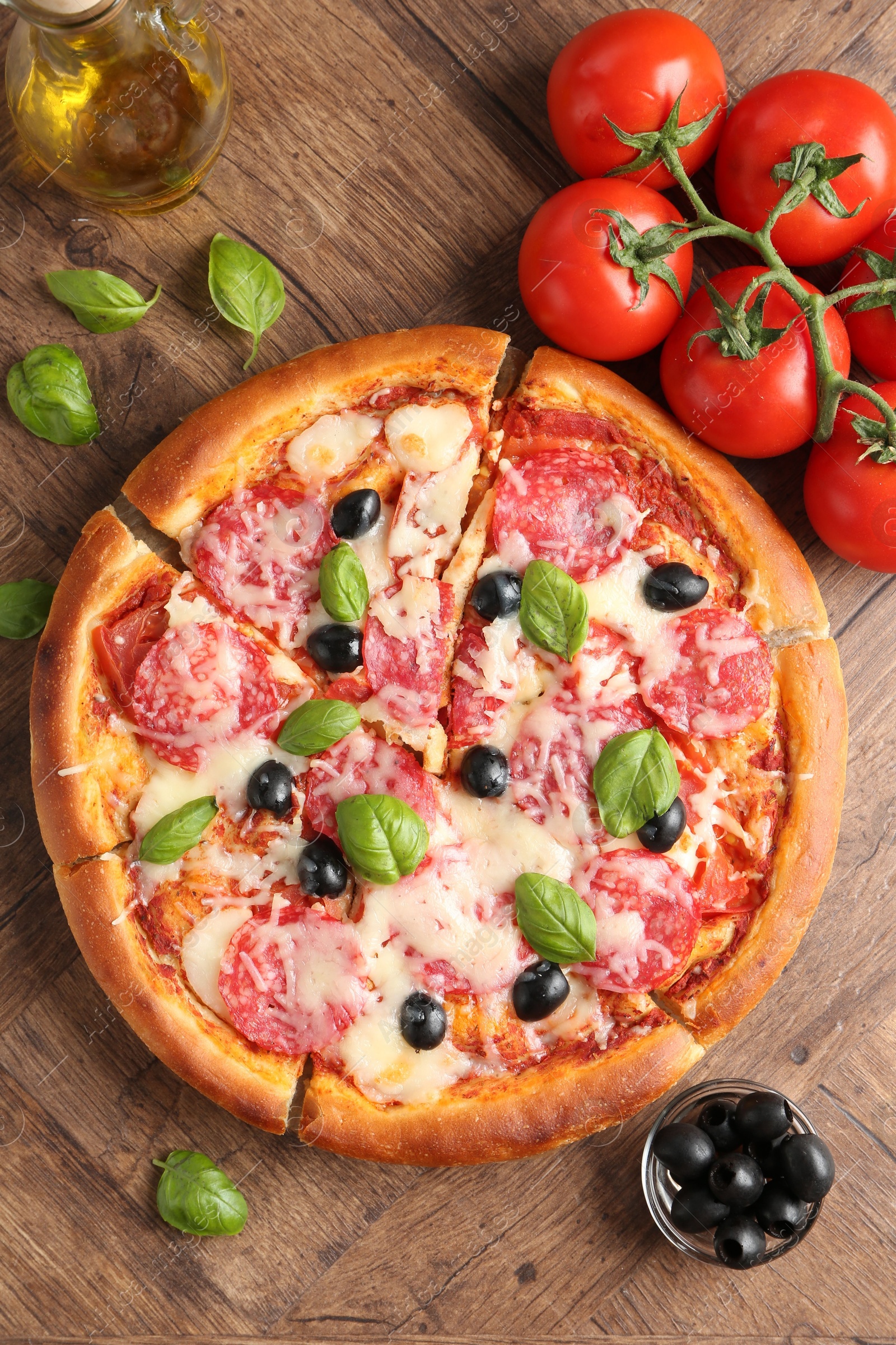 Tasty pizza and ingredients on wooden table, flat lay Photo of Tasty pizza and ingredients on wooden table, flat lay