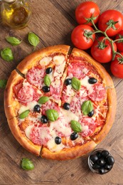 Photo of Tasty pizza and ingredients on wooden table, flat lay