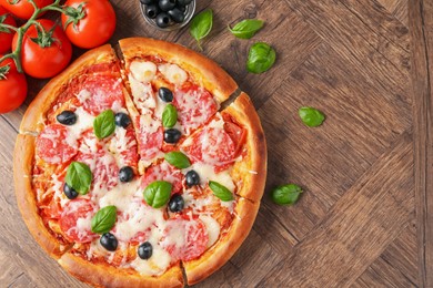 Photo of Tasty pizza and ingredients on wooden table, flat lay. Space for text