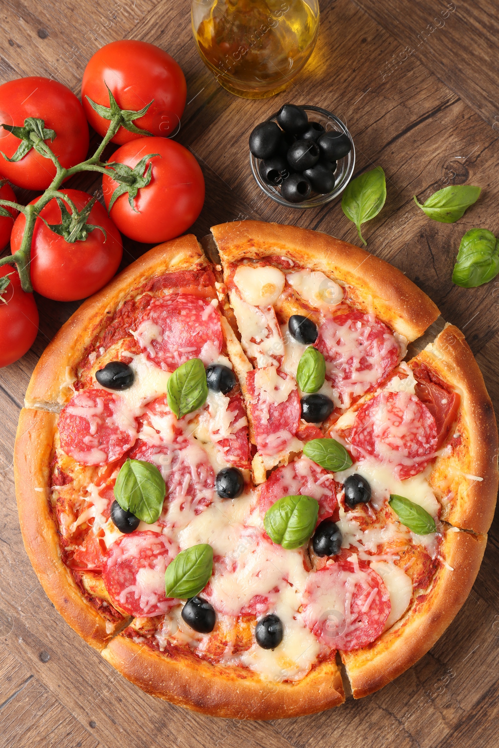 Tasty pizza and ingredients on wooden table, flat lay Photo of Tasty pizza and ingredients on wooden table, flat lay