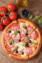 Photo of Tasty pizza and ingredients on wooden table, flat lay