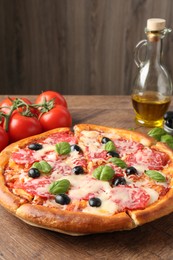 Photo of Tasty pizza and ingredients on wooden table, closeup