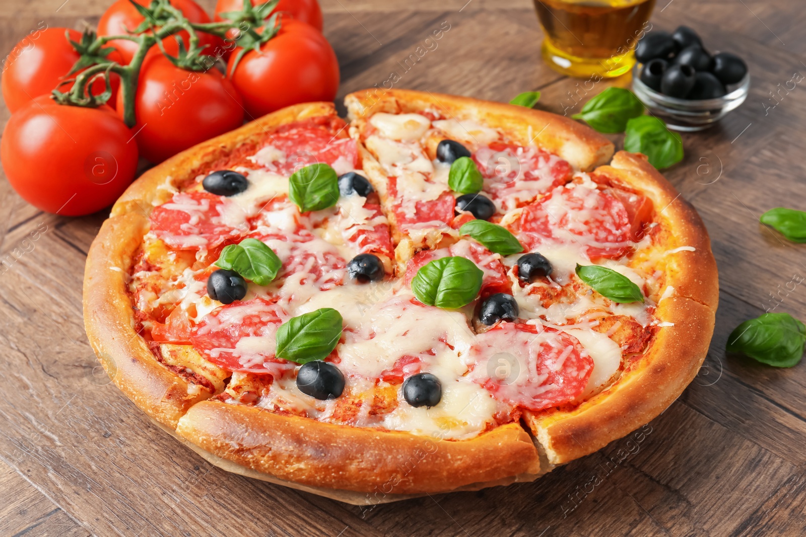 Tasty pizza and ingredients on wooden table, closeup Photo of Tasty pizza and ingredients on wooden table, closeup