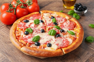 Photo of Tasty pizza and ingredients on wooden table, closeup