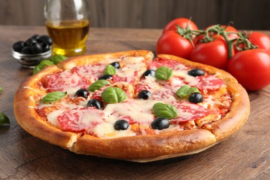Photo of Tasty pizza and ingredients on wooden table, closeup