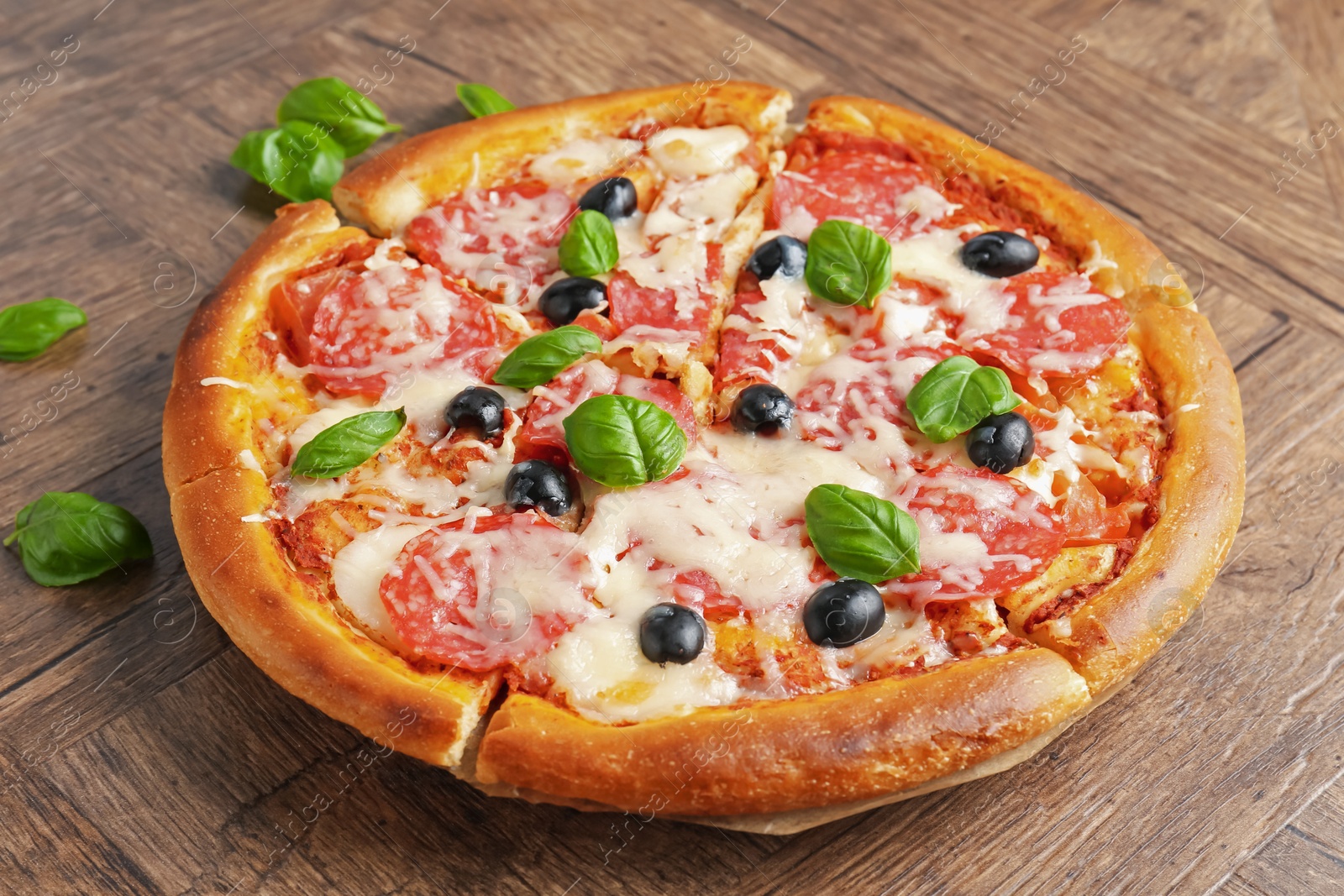 Tasty pizza with salami, cheese, basil and olives on wooden table, closeup Photo of Tasty pizza with salami, cheese, basil and olives on wooden table, closeup