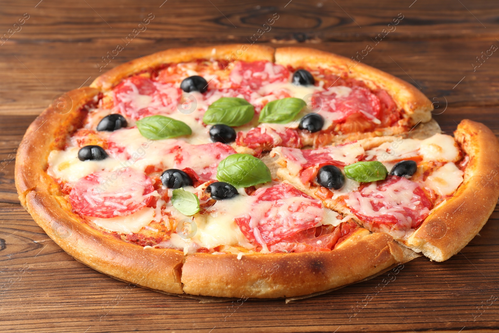 Tasty pizza with salami, cheese, basil and olives on wooden table, closeup Photo of Tasty pizza with salami, cheese, basil and olives on wooden table, closeup