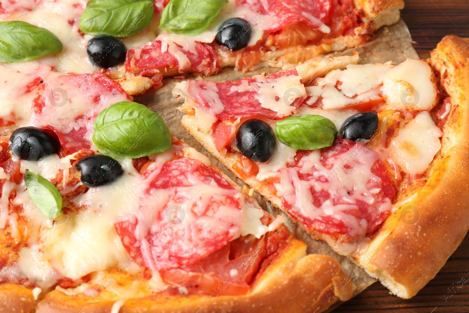 Tasty pizza with salami, cheese, basil and olives on table, closeup Photo of Tasty pizza with salami, cheese, basil and olives on table, closeup