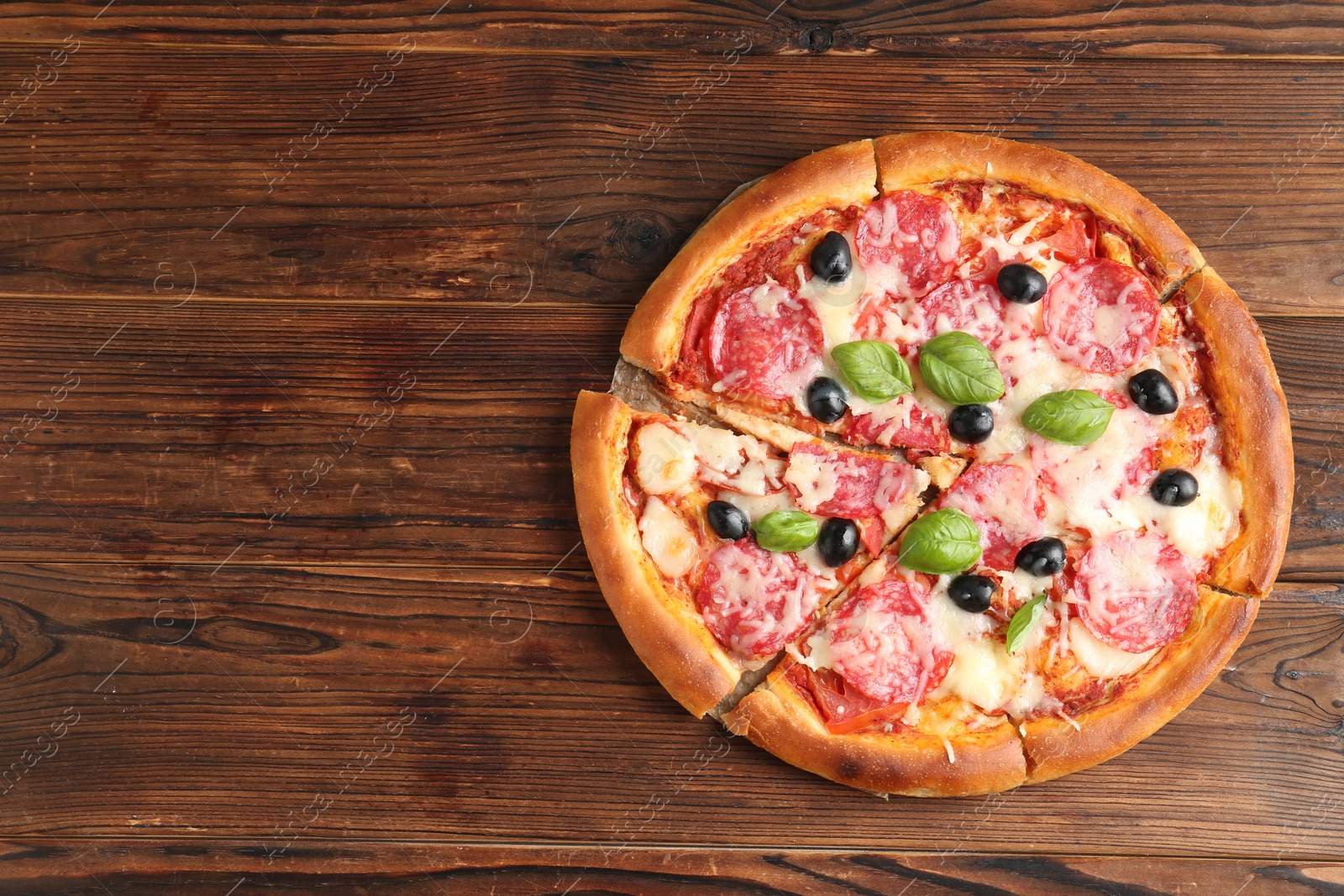 Tasty pizza with salami, cheese, basil and olives on wooden table, top view. Space for text Photo of Tasty pizza with salami, cheese, basil and olives on wooden table, top view. Space for text