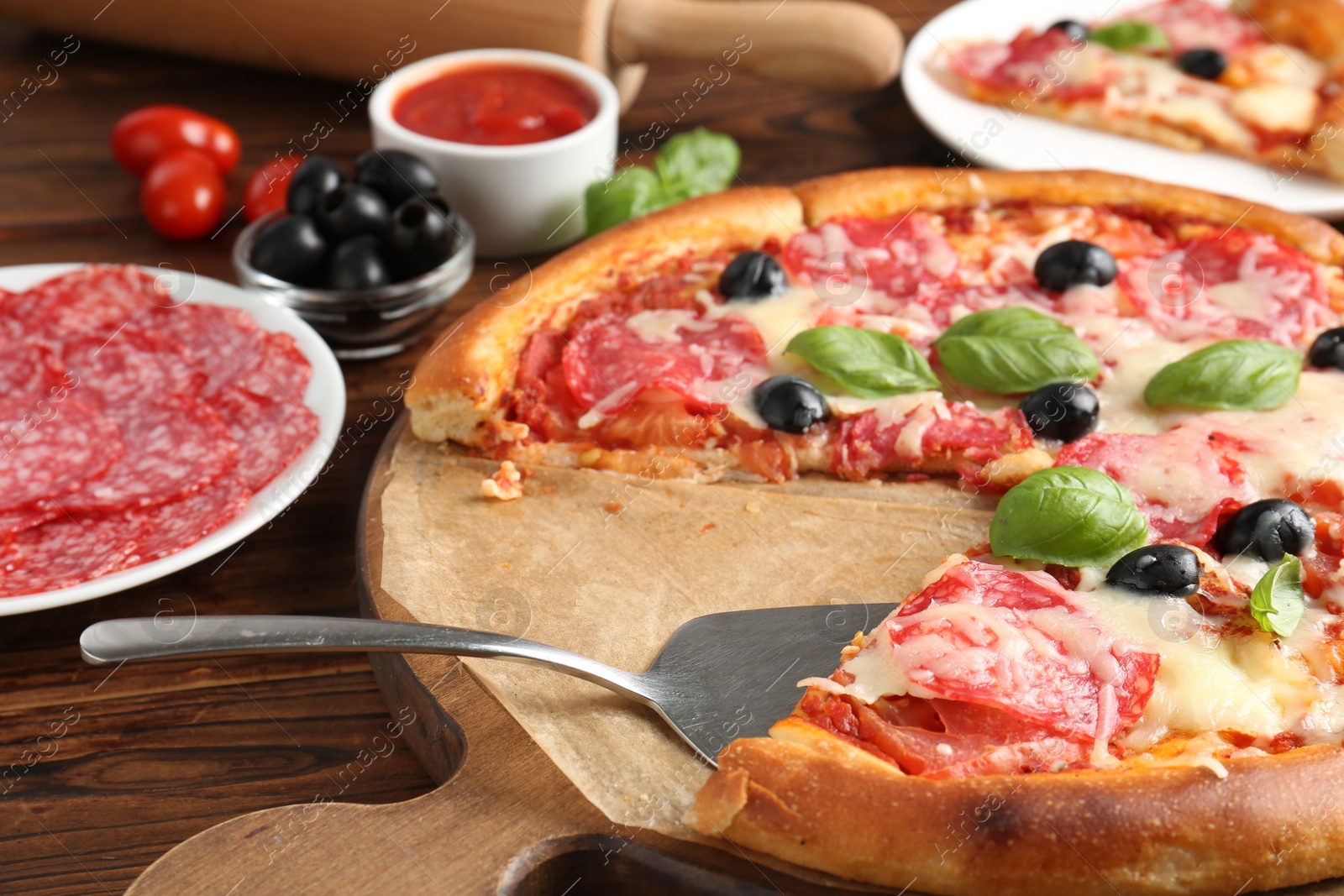 Tasty pizza and ingredients on wooden table, closeup Photo of Tasty pizza and ingredients on wooden table, closeup