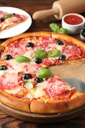 Photo of Tasty pizza and ingredients on wooden table, closeup
