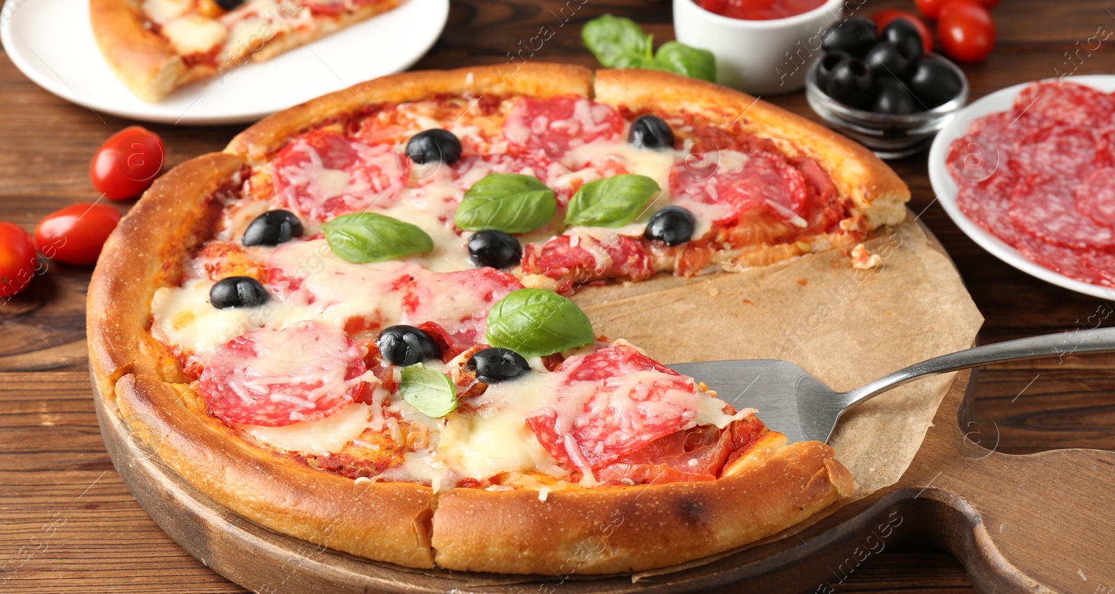 Tasty pizza and ingredients on wooden table, closeup Photo of Tasty pizza and ingredients on wooden table, closeup