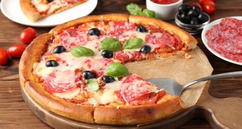 Photo of Tasty pizza and ingredients on wooden table, closeup