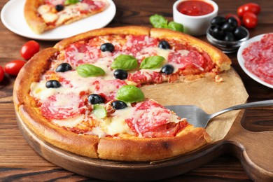 Photo of Tasty pizza and ingredients on wooden table, closeup