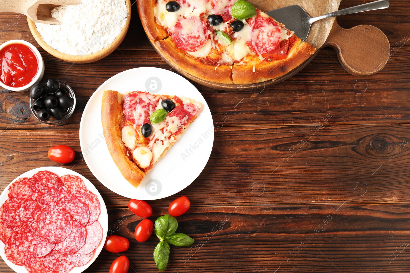 Tasty pizza and ingredients on wooden table, flat lay. Space for text Photo of Tasty pizza and ingredients on wooden table, flat lay. Space for text