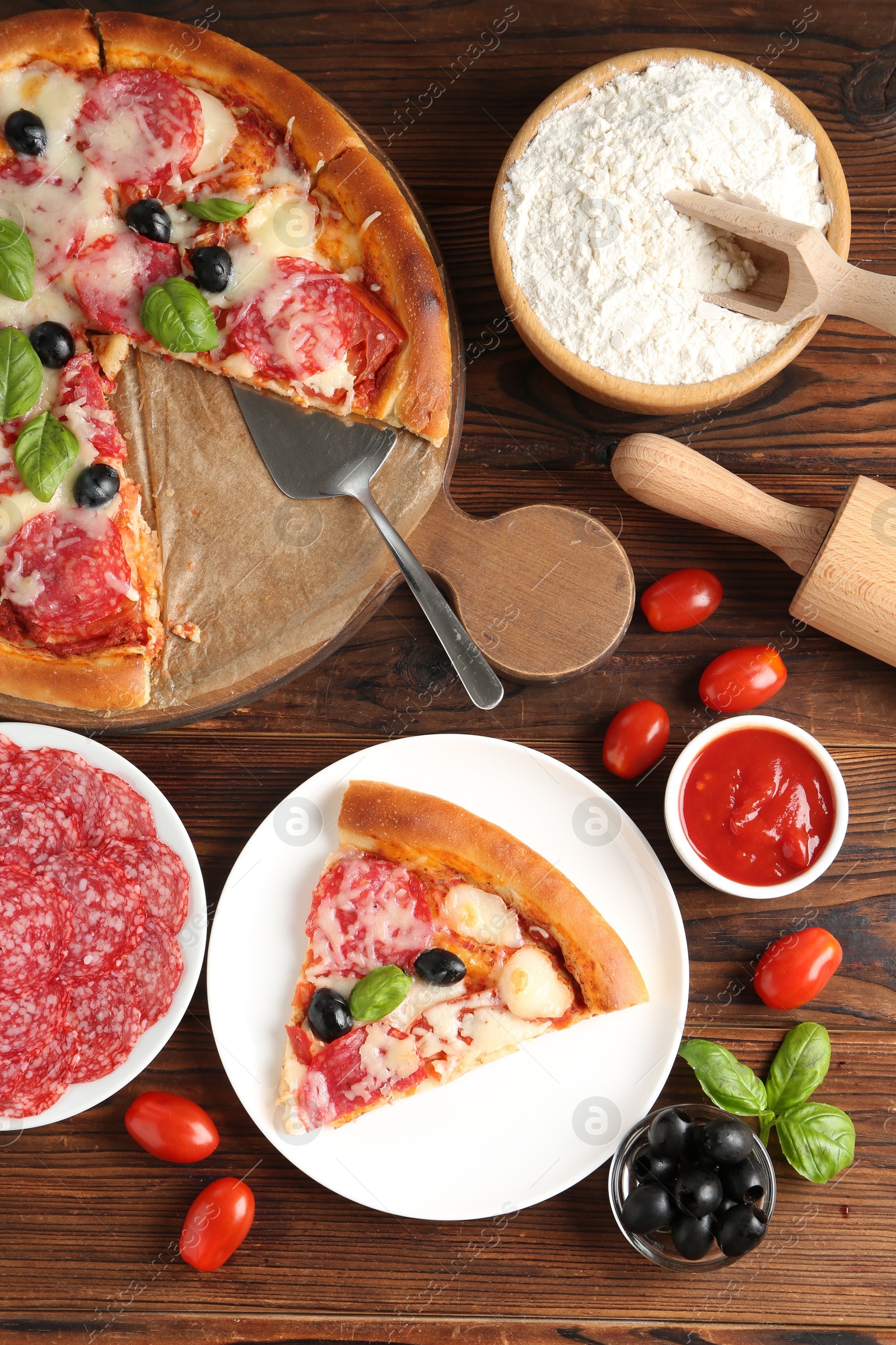 Tasty pizza and ingredients on wooden table, flat lay Photo of Tasty pizza and ingredients on wooden table, flat lay