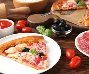 Photo of Tasty pizza and ingredients on wooden table, closeup