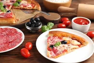 Photo of Tasty pizza and ingredients on wooden table, closeup