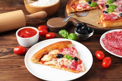 Photo of Tasty pizza and ingredients on wooden table, closeup