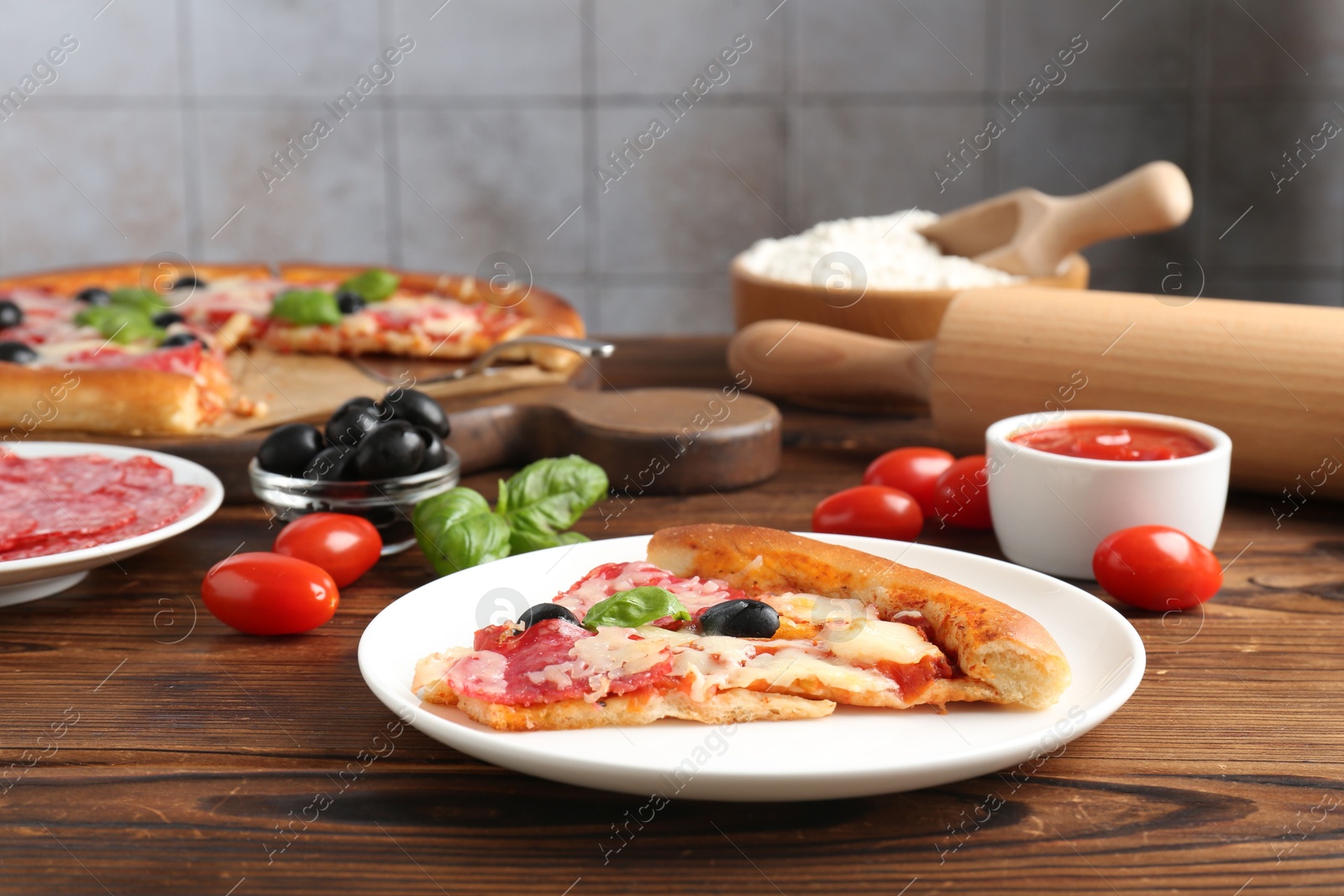 Tasty pizza and ingredients on wooden table, closeup Photo of Tasty pizza and ingredients on wooden table, closeup