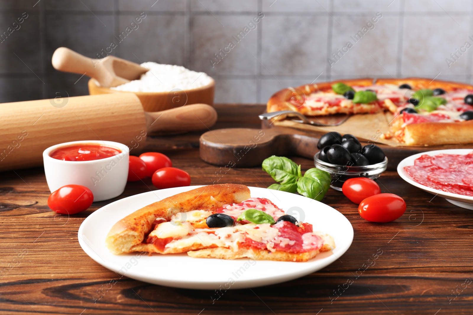 Tasty pizza and ingredients on wooden table, closeup Photo of Tasty pizza and ingredients on wooden table, closeup
