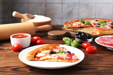 Photo of Tasty pizza and ingredients on wooden table, closeup