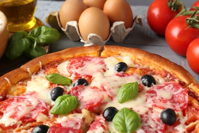 Photo of Tasty pizza and ingredients on grey wooden table, closeup