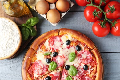 Photo of Tasty pizza and ingredients on grey wooden table, flat lay
