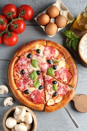 Photo of Tasty pizza and ingredients on grey wooden table, flat lay