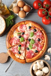 Photo of Tasty pizza and ingredients on grey wooden table, flat lay