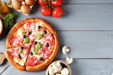 Photo of Tasty pizza and ingredients on grey wooden table, flat lay. Space for text