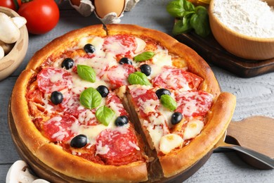 Photo of Tasty pizza and ingredients on grey wooden table, closeup