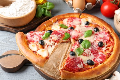 Photo of Tasty pizza and ingredients on grey wooden table, closeup